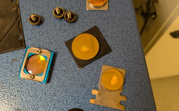 Mercury 3 laser mirrors and lens removed showing burn damage before service